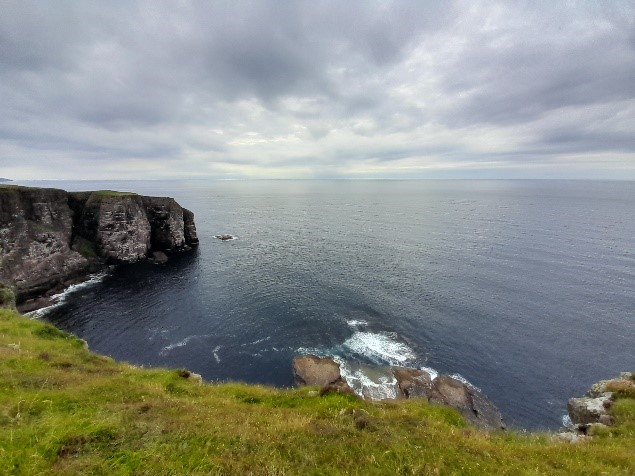 A wide view of sea cliffs overlooking the water.