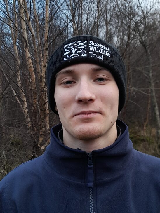 Close-up of a young man wearing a Scottish Wildlife Trust beanie hat.
