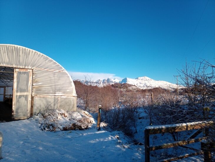 Snow covered ground is shown in this image with a backdrop of snowy mountains in Scotland. 