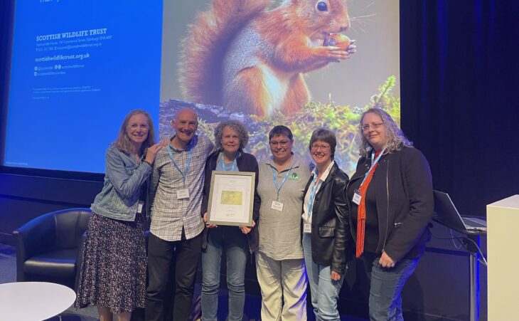 Five volunteers from the Nature Ninjas, along with Cumbernauld Living Landscape Project Manager, Tracy Lambert, are standing side by side holding their framed certificate.