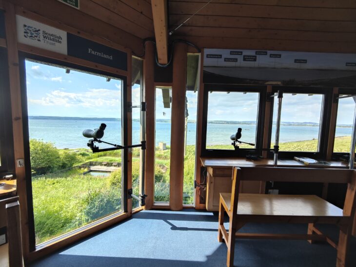 A view from the Montrose Basin Visitor Centre. Inside there are spotting scopes and benches. The view out of the large windows looks across the large tidal basin at Montrose.