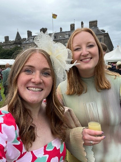 Two of the Scottish Wildlife Trust's Young Leaders attending His Majesty The King’s Garden Party at Holyrood Palace. The building of Holyrood Palace is visible in the background.