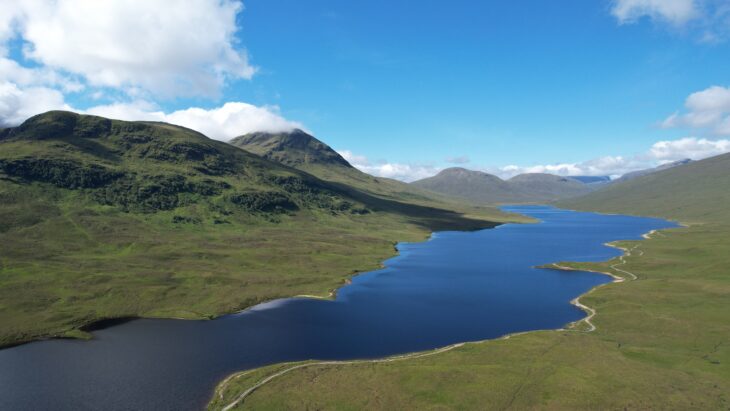 A loch stretching into the distance, surrounded by upland moors and mountain peaks.