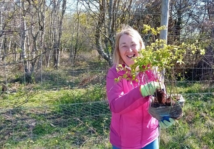 Action for Nature volunteer, Lynn Telfer, holding a tree sapling.