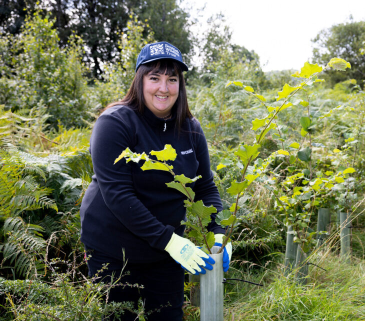 Action for Nature volunteer, Roz Asli, putting a protective guard around a young tree.