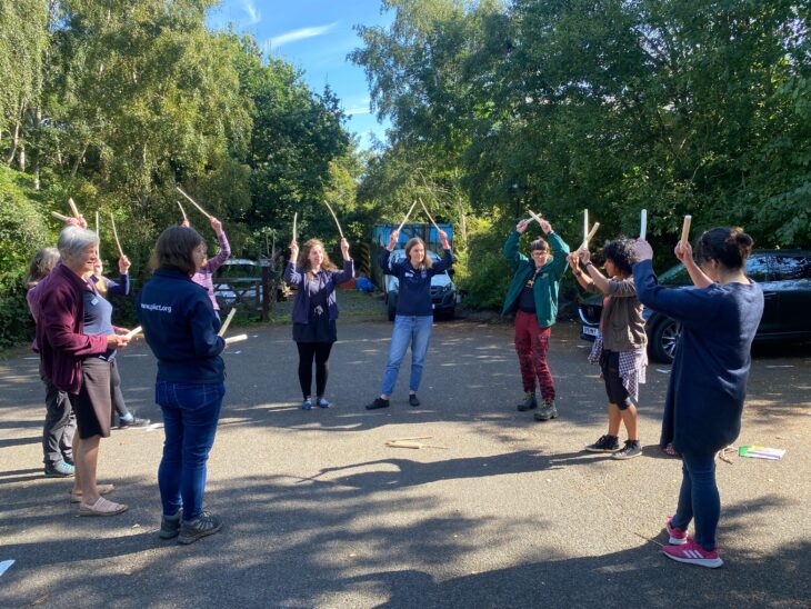Wildlife Watch volunteers standing in a circle playing a game with sticks