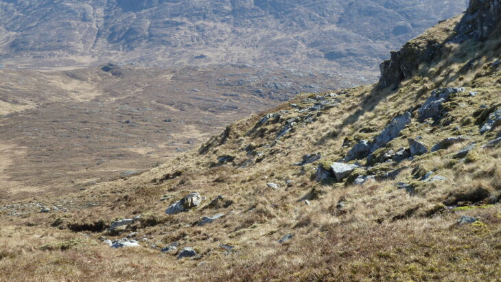 A photo taken at the Scottish Wildlife Trust's Rahoy Hills Reserve. The view looks across a glen with rocky grass in the foreground and rolling hills beyond.